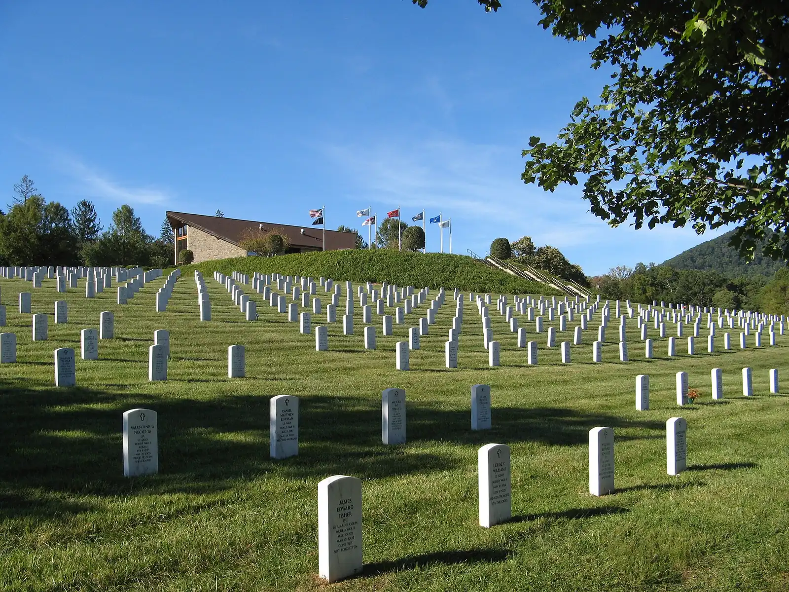 Rows of headstones below the flags and committal shelter at the Western Carolina State Veterans Cemetery in Black Mountain.
