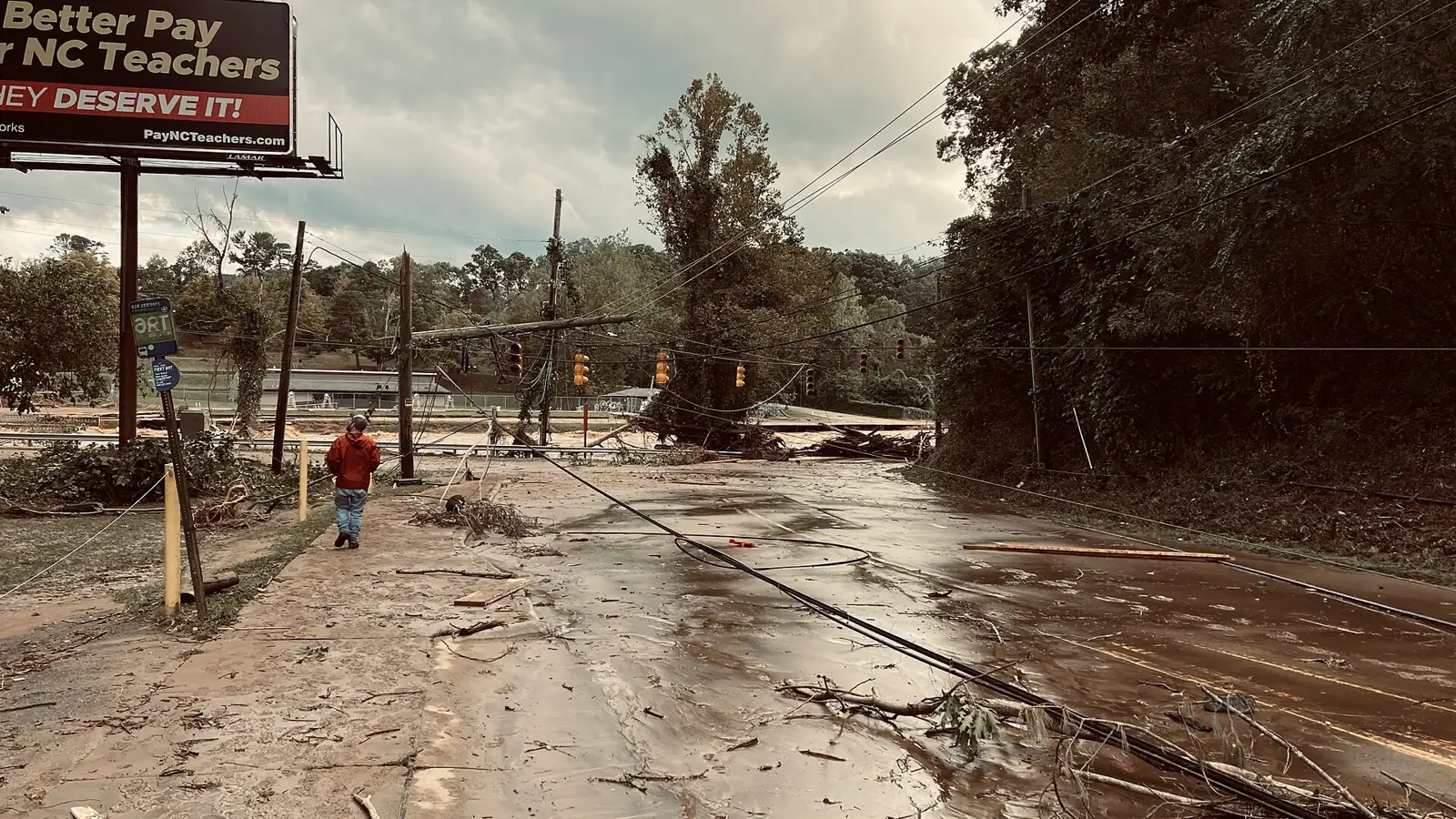 Downed utility poles and power lines across a road near the Swannanoa River in East Asheville after Hurricane Helene.